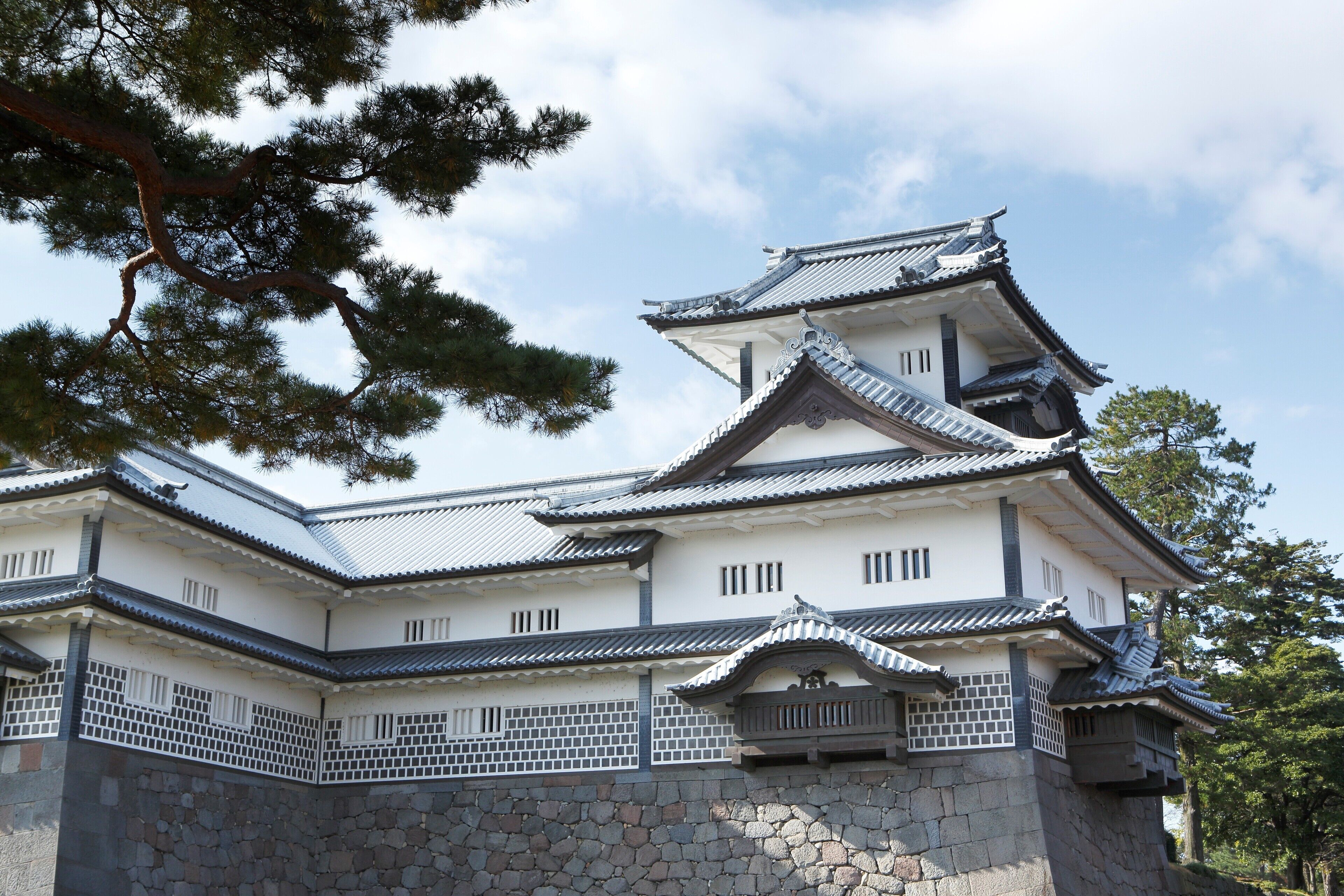 A traditional Japanese castle with multiple levels, stone walls, and tiled roofs.