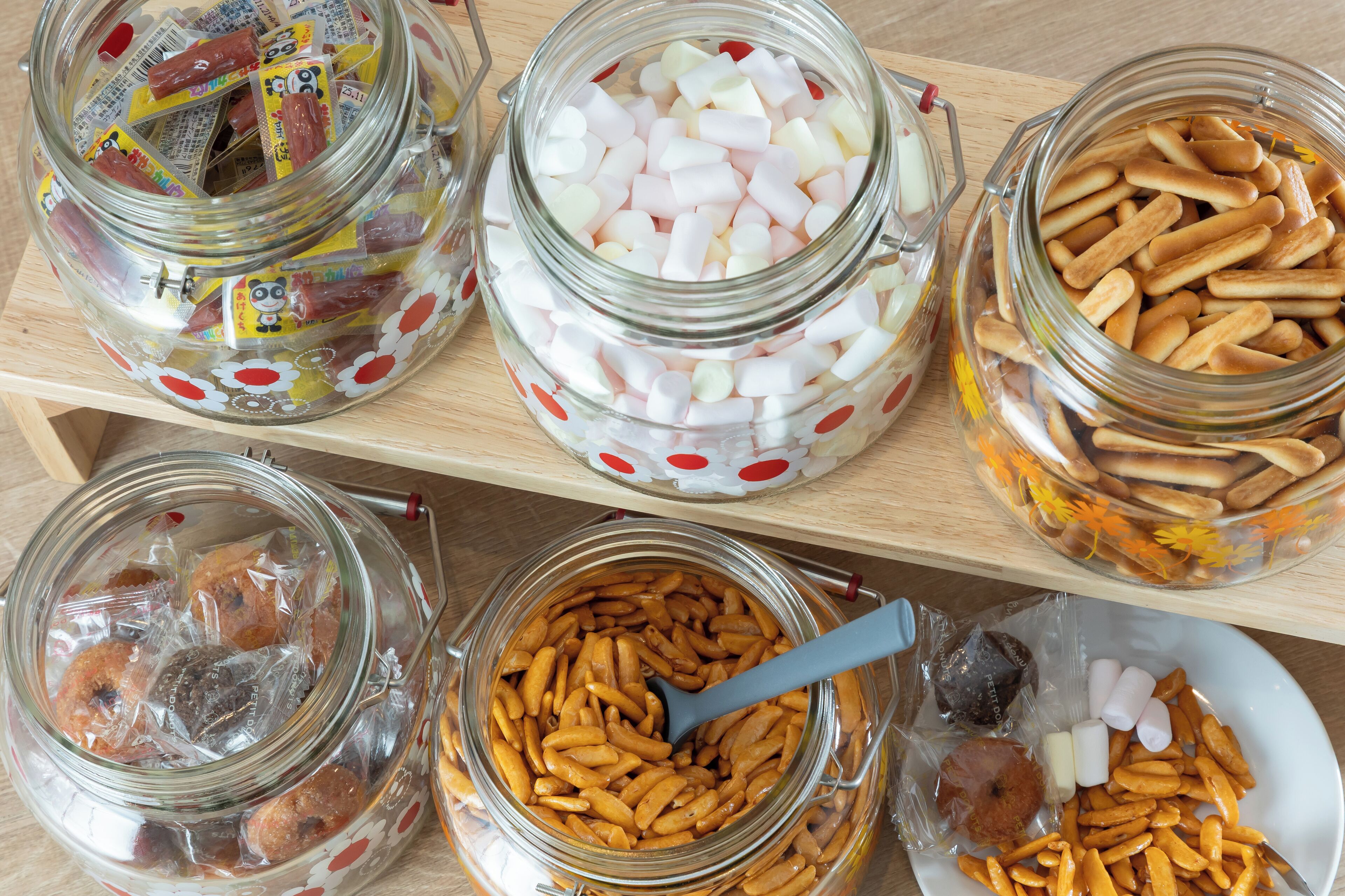 A variety of food items in glass jars on a wooden shelf.