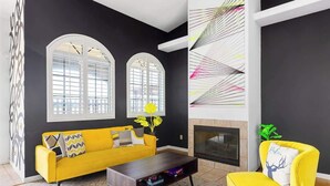 Un salon moderne avec un canapé jaune, une table basse et une cheminée.