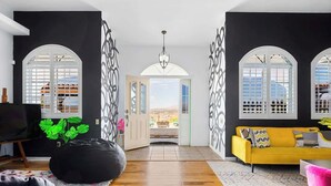 Un salon moderne avec un plancher en bois, un fauteuil en forme de sac de haricots noir, un canapé jaune et un téléviseur posé sur un meuble.