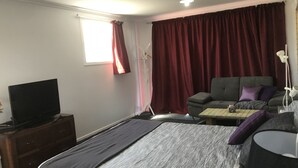 Une chambre d’hôtel avec un lit, un téléviseur posé sur une commode, un canapé et une petite table.