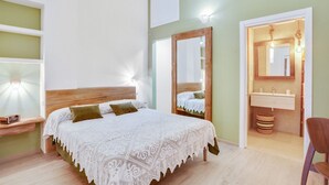 Ein Schlafzimmer mit Bett, Nachttisch, Spiegel und einem Badezimmer mit Waschbecken und Spiegel.