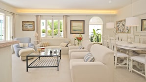 Un salon comprenant un canapé, des fauteuils, une table basse et un coin repas avec une table et des chaises.