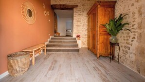 Un pasillo con un banco de madera, una cesta de mimbre, un armario de madera y una planta en maceta.