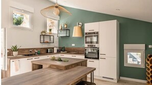 Una cocina moderna con una isla central, horno empotrado y una lámpara colgante.