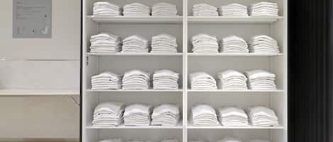 Uma estante branca com toalhas brancas dobradas de forma organizada.