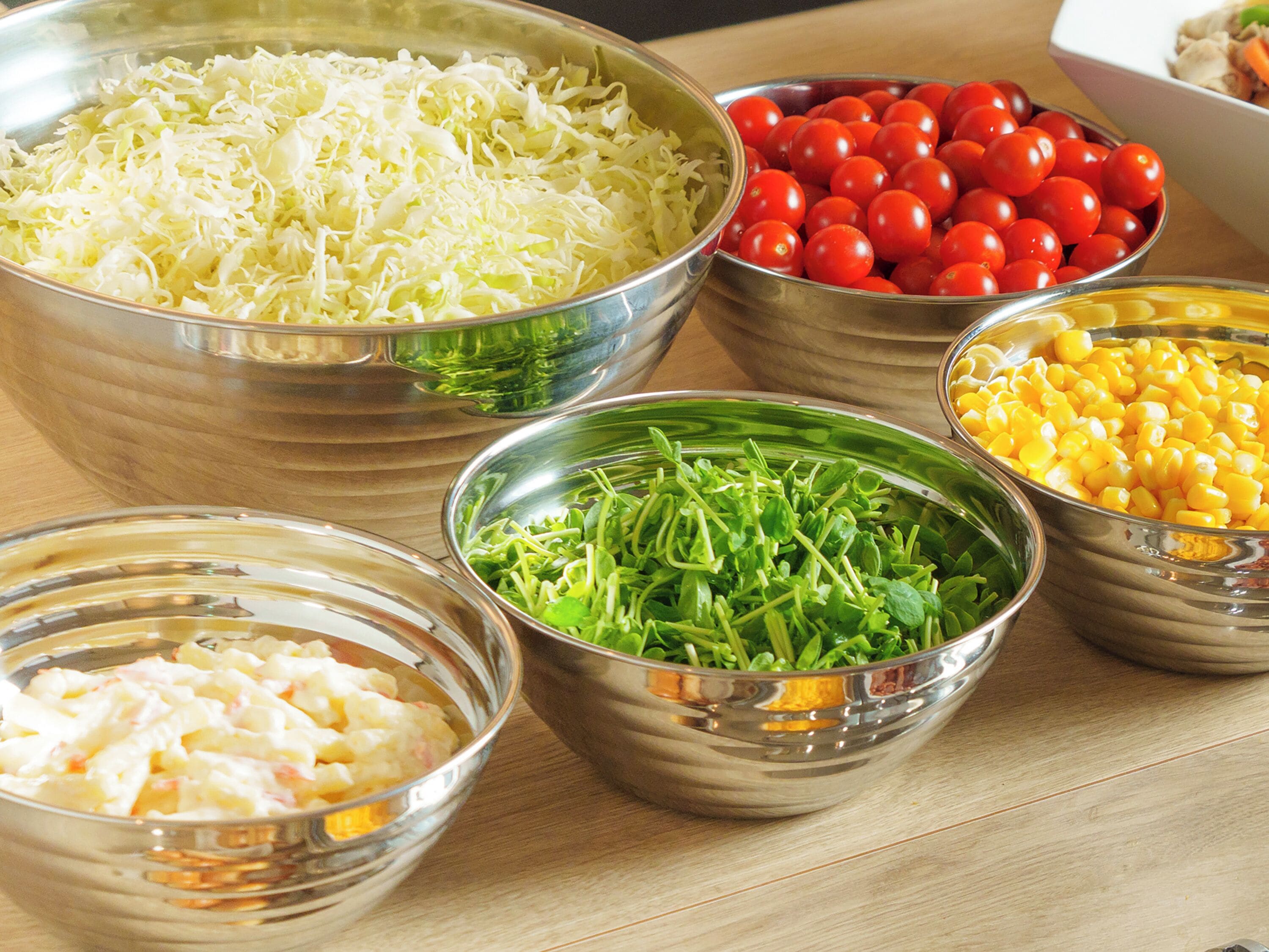 A table with various food items in metal bowls.