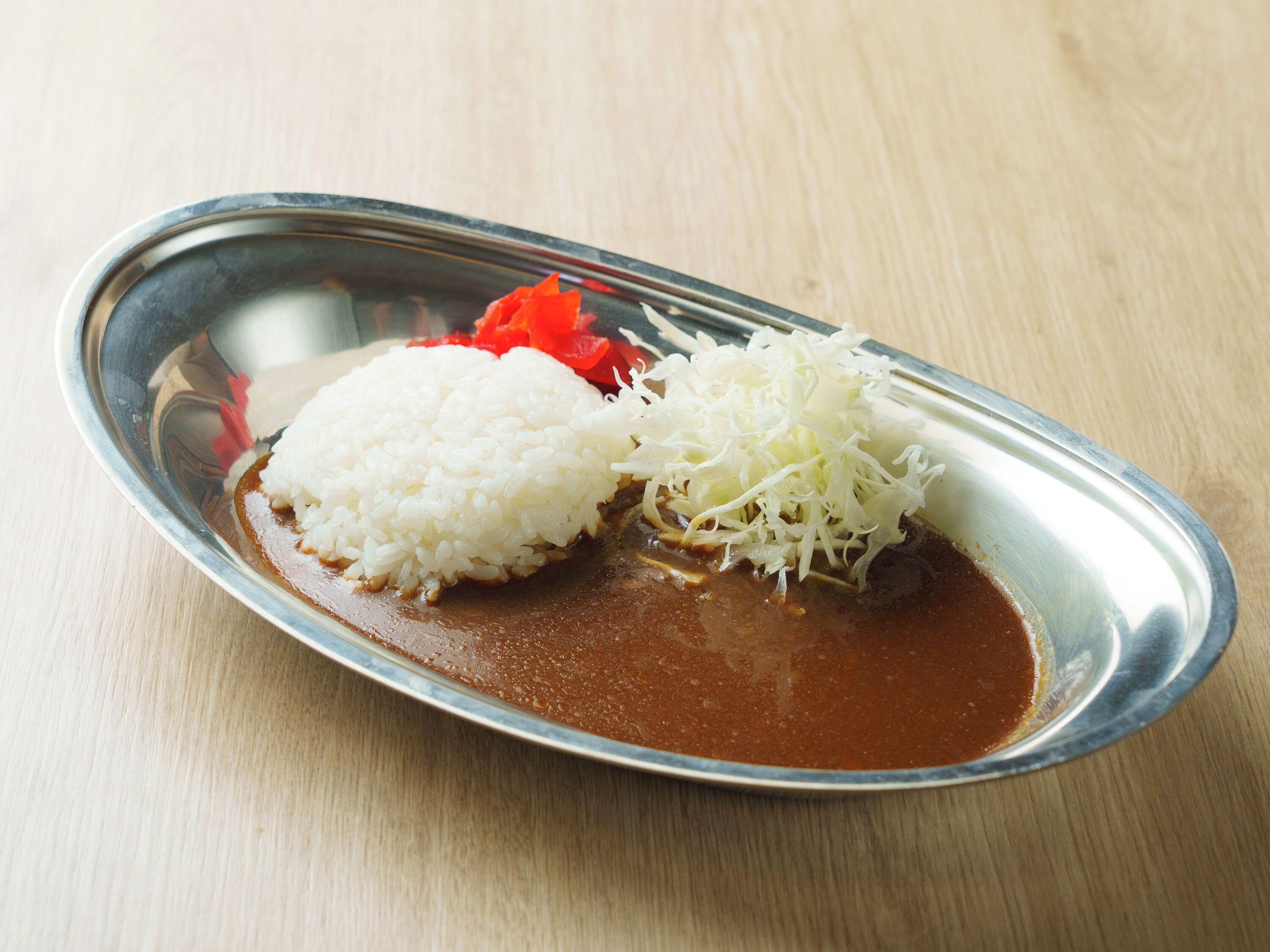 Un plato con arroz blanco, queso rallado y pimientos rojos sobre una mesa de madera.