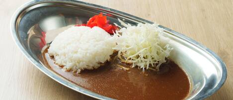 Un plato con arroz blanco, queso rallado y pimientos rojos sobre una mesa de madera.