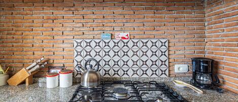 Cuina amb fogó de gas, cafetera i salabost.