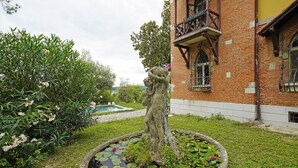 Un jardín con una fuente, un edificio de ladrillo y una piscina.