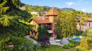 Una villa con jardín, piscina y vistas de las colinas circundantes.