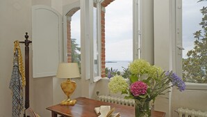 Una habitación con una mesa de madera, una lámpara, un libro y un jarrón de flores.