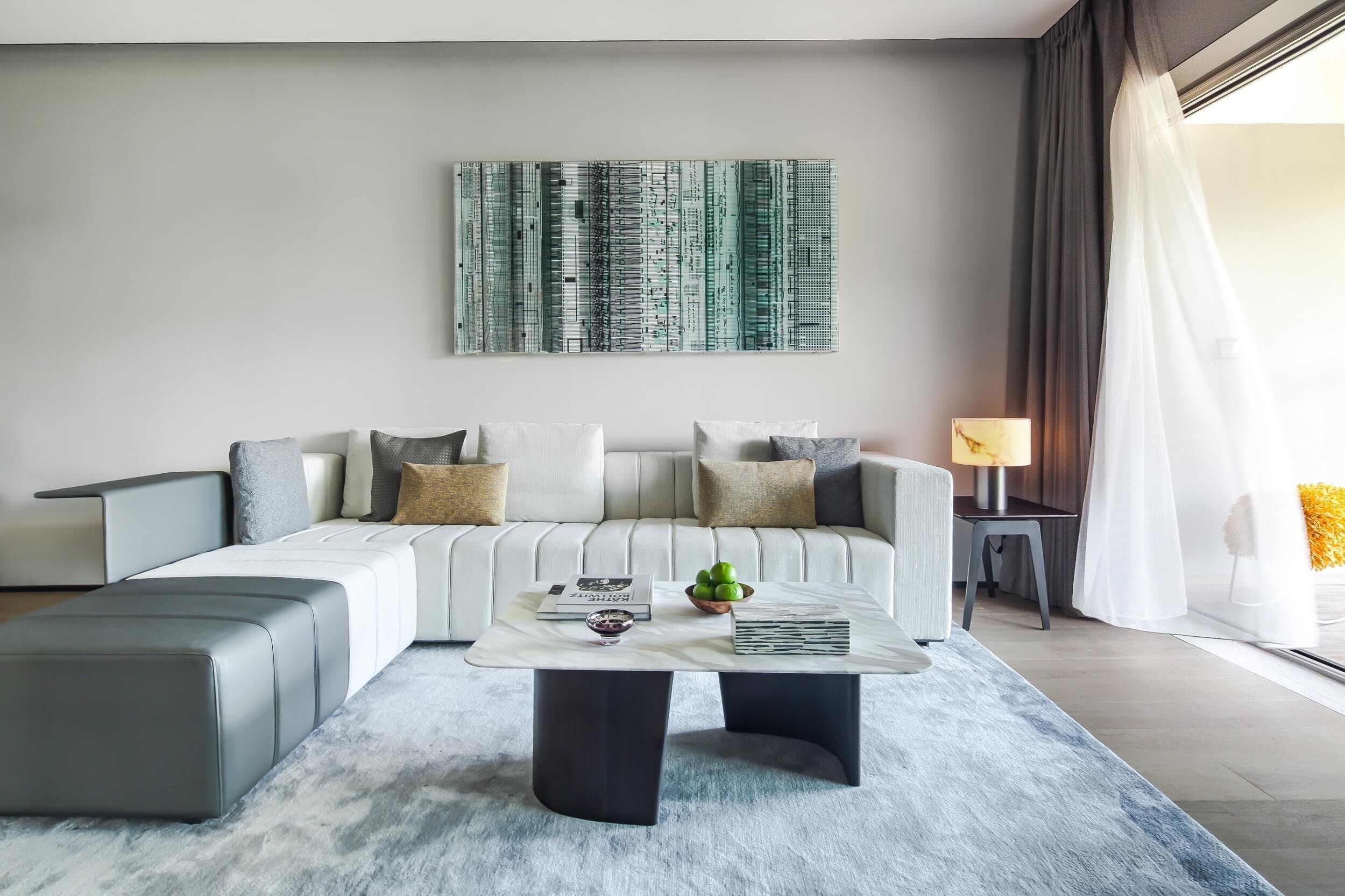 A modern living room with a sofa, a coffee table, and a large abstract painting on the wall.