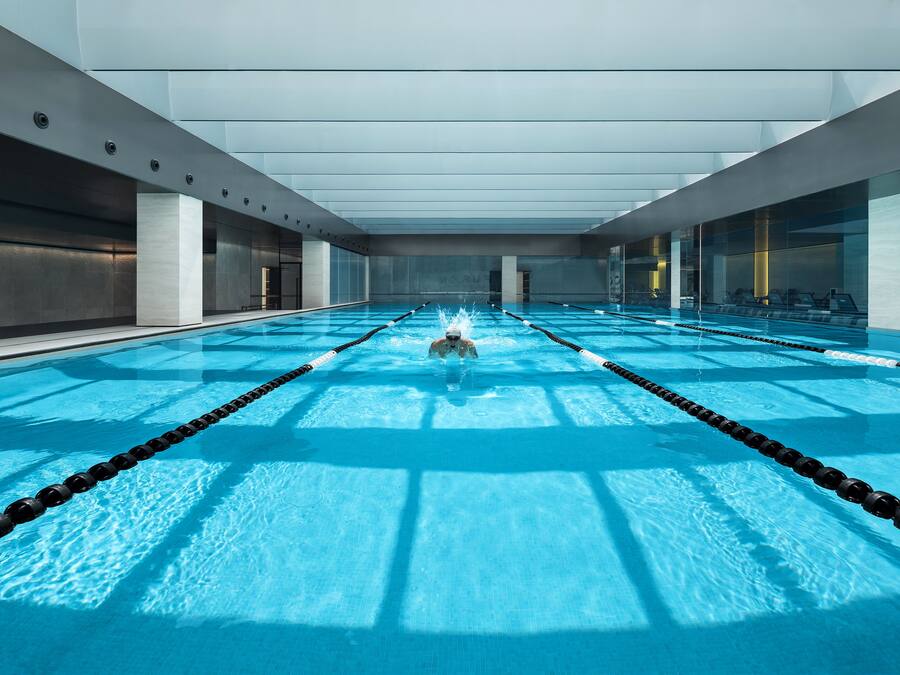 A modern indoor swimming pool with clear lanes and a central water feature.