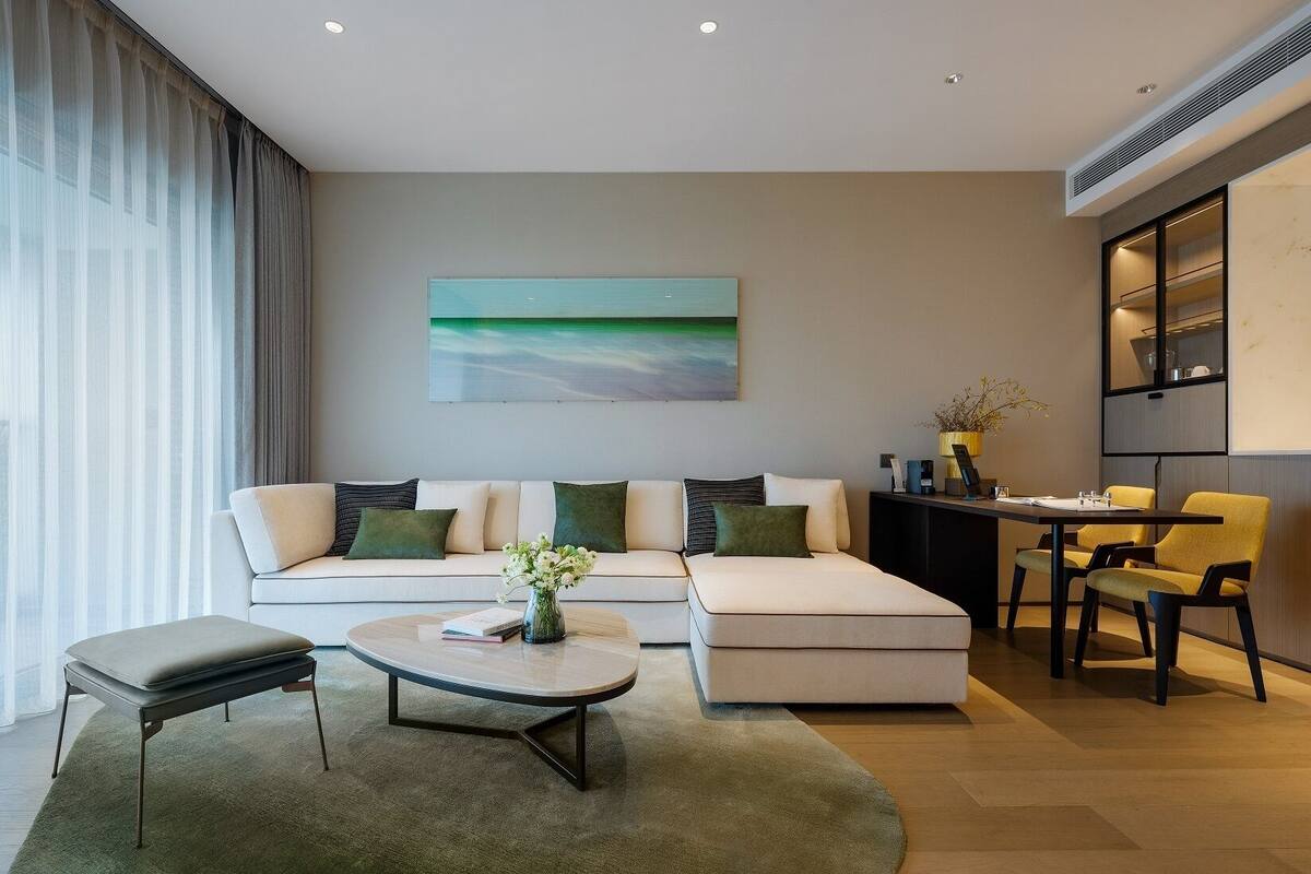 A modern living room with a sectional sofa, a coffee table, and a dining area with chairs.