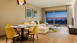Una sala moderna con comedor, un conjunto de sofá, una mesa de centro y un ventanal con vistas a la ciudad.