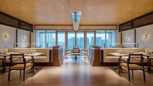 Un comedor moderno con techos altos, ventanas amplias y una mesa de comedor central.