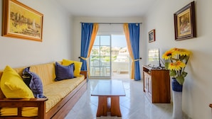 Un salon avec un canapé, une table basse et une vue sur un balcon.