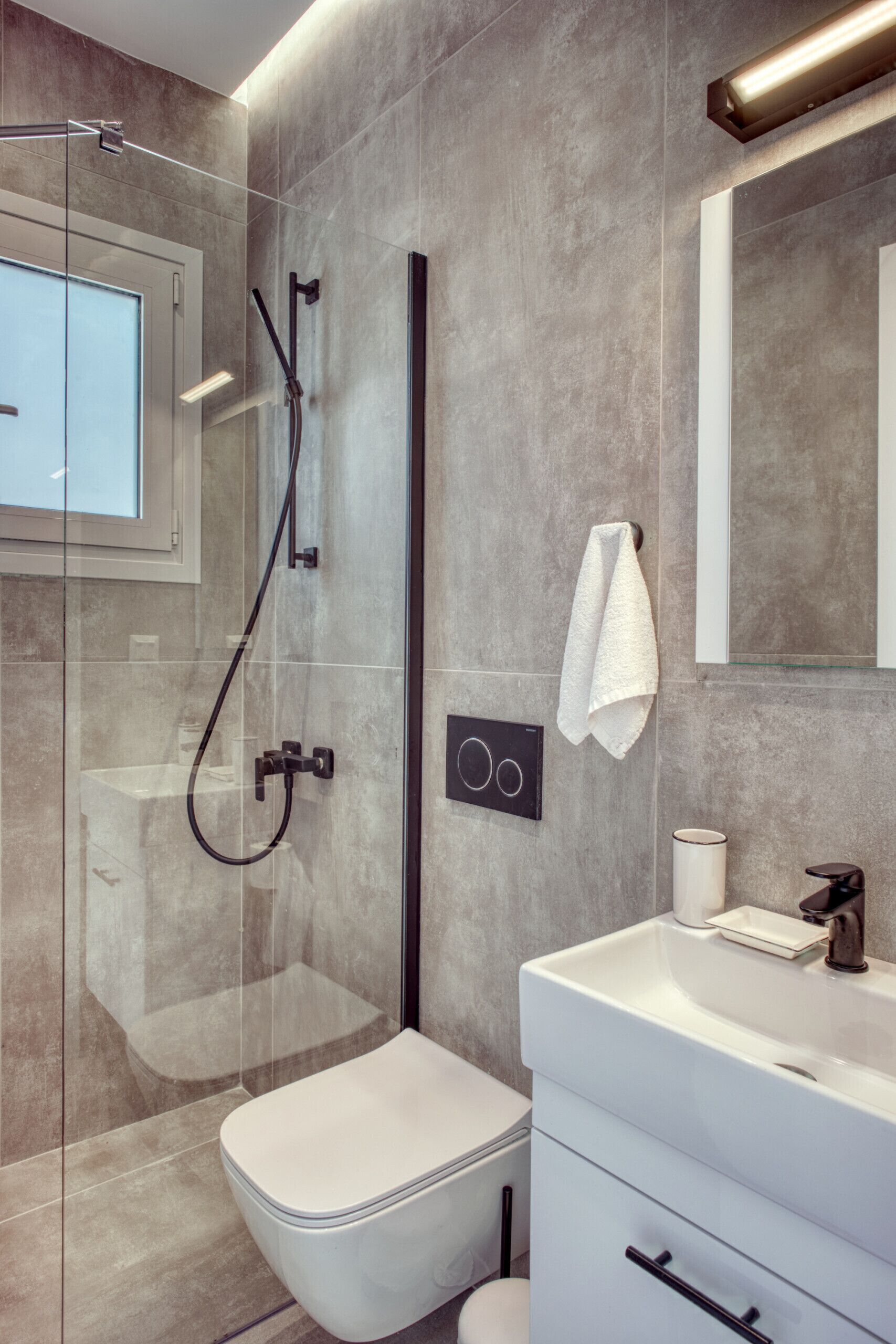 Une salle de bain moderne avec une douche à parois de verre, des toilettes blanches et un meuble-lavabo avec un miroir.