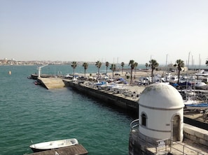 A marina with boats docked, a lighthouse, and a clear view of the coastline.