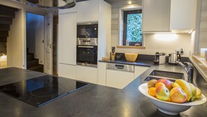 Cocina moderna con horno integrado, lavavajillas y un cuenco de fruta en la encimera.