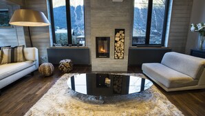 Una sala de estar moderna con chimenea, ventanas amplias, una mesa de centro redonda y un sofá.