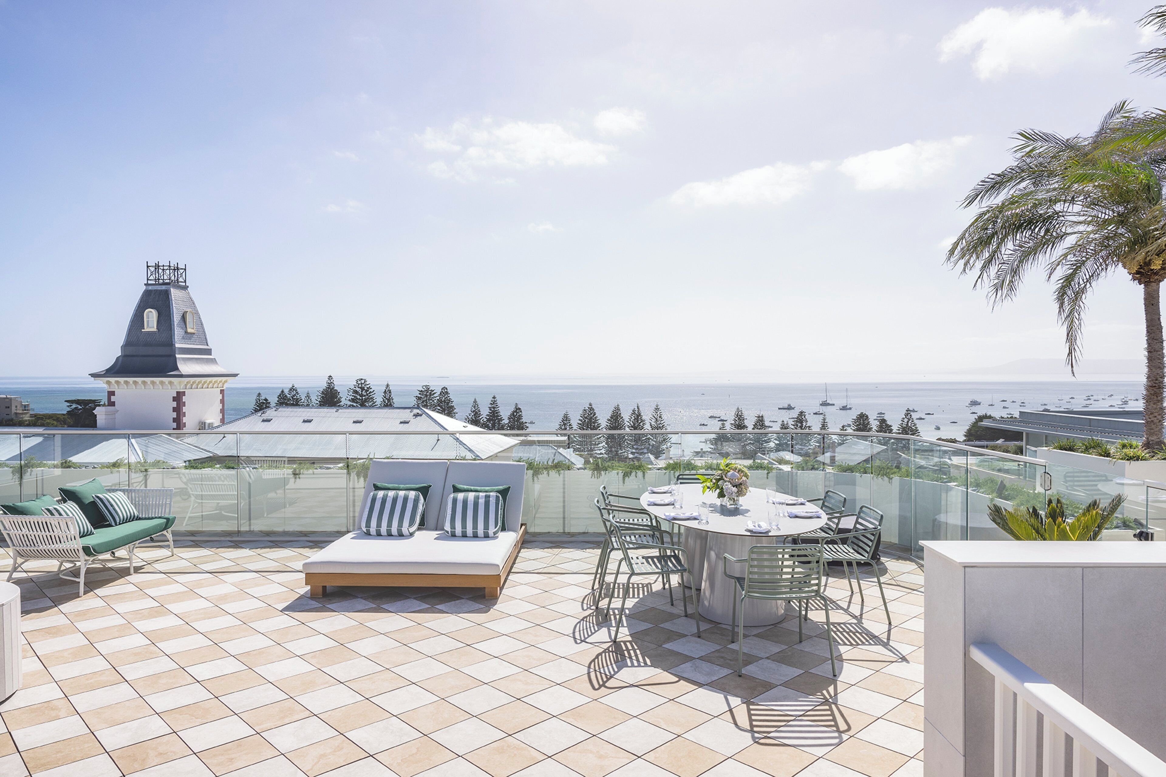 A terrace with a dining table, chairs, and a sofa with cushions.
