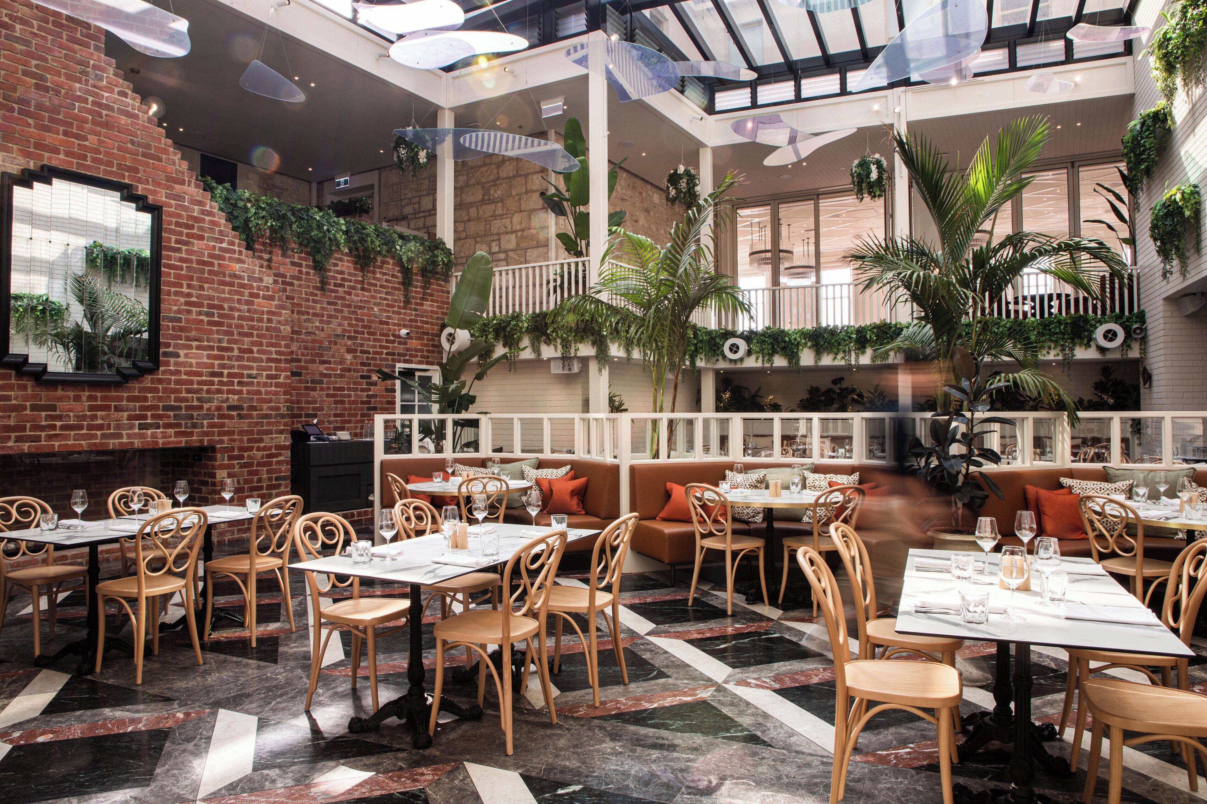 A restaurant with brick walls, wooden furniture, and a mix of indoor and outdoor seating.