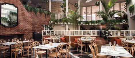 A restaurant with brick walls, wooden furniture, and a mix of indoor and outdoor seating.