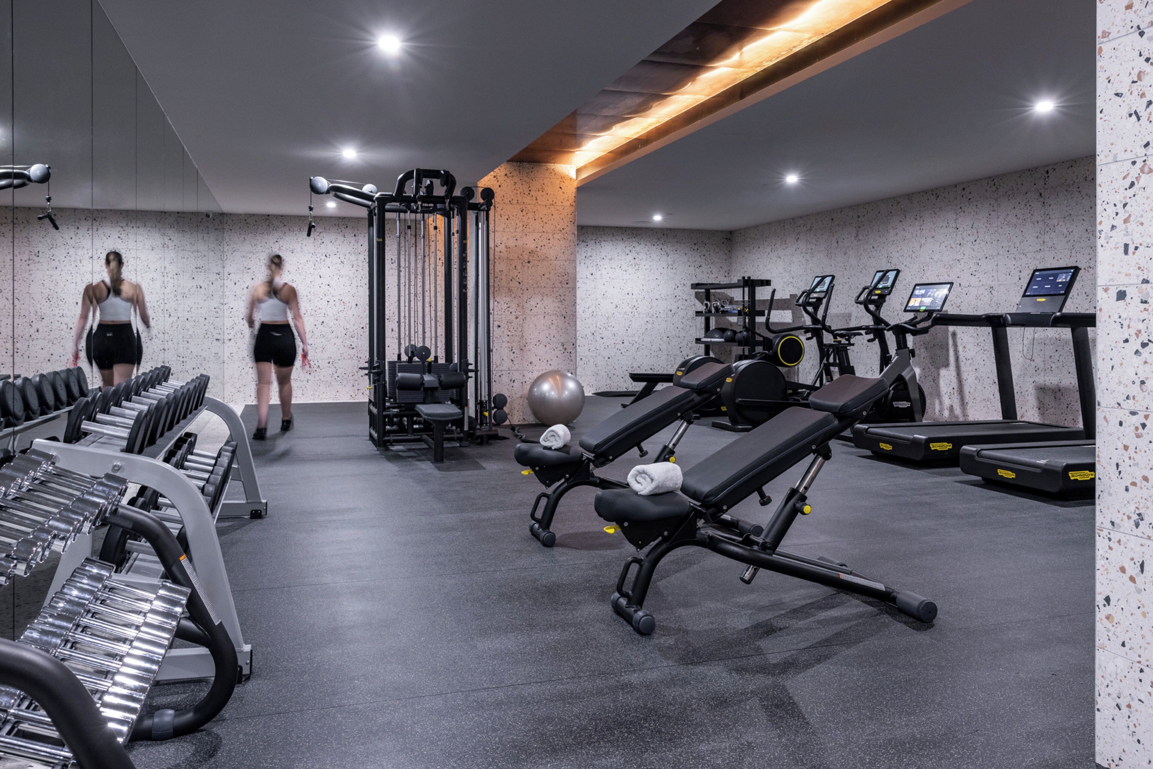 A gym with exercise equipment, treadmills, and weights.