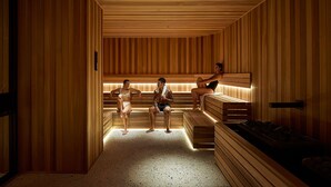 Een sauna met houten wanden en banken, een bank met een handdoek, en een bank voorzien van een handdoek.