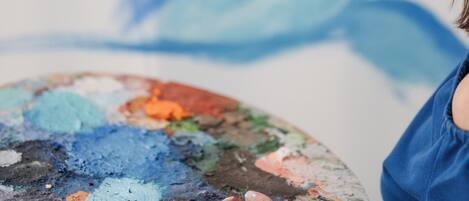 A person painting a mural with a palette of various colors.