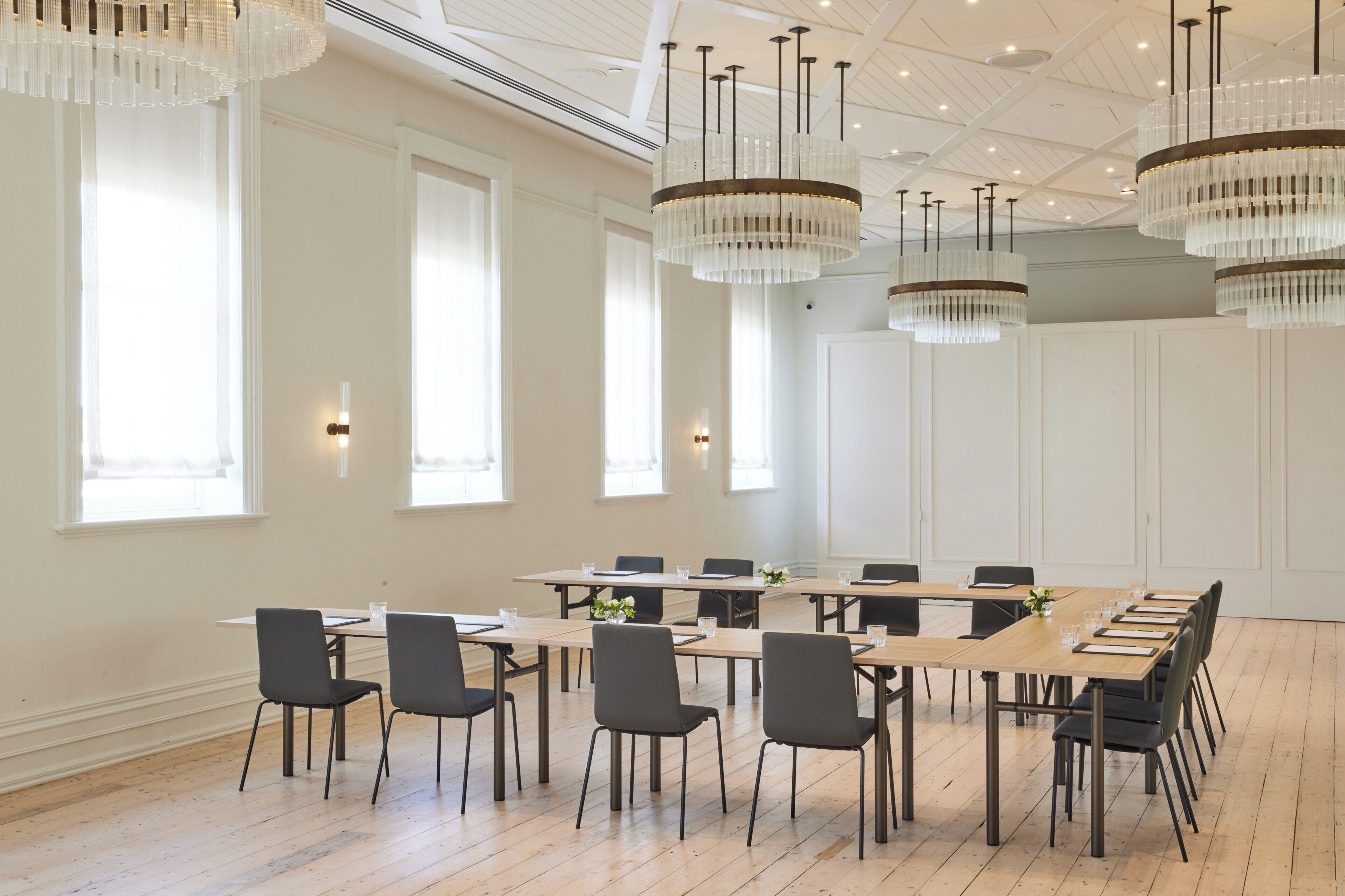Une salle de conférence avec une longue table, des chaises et des lustres.