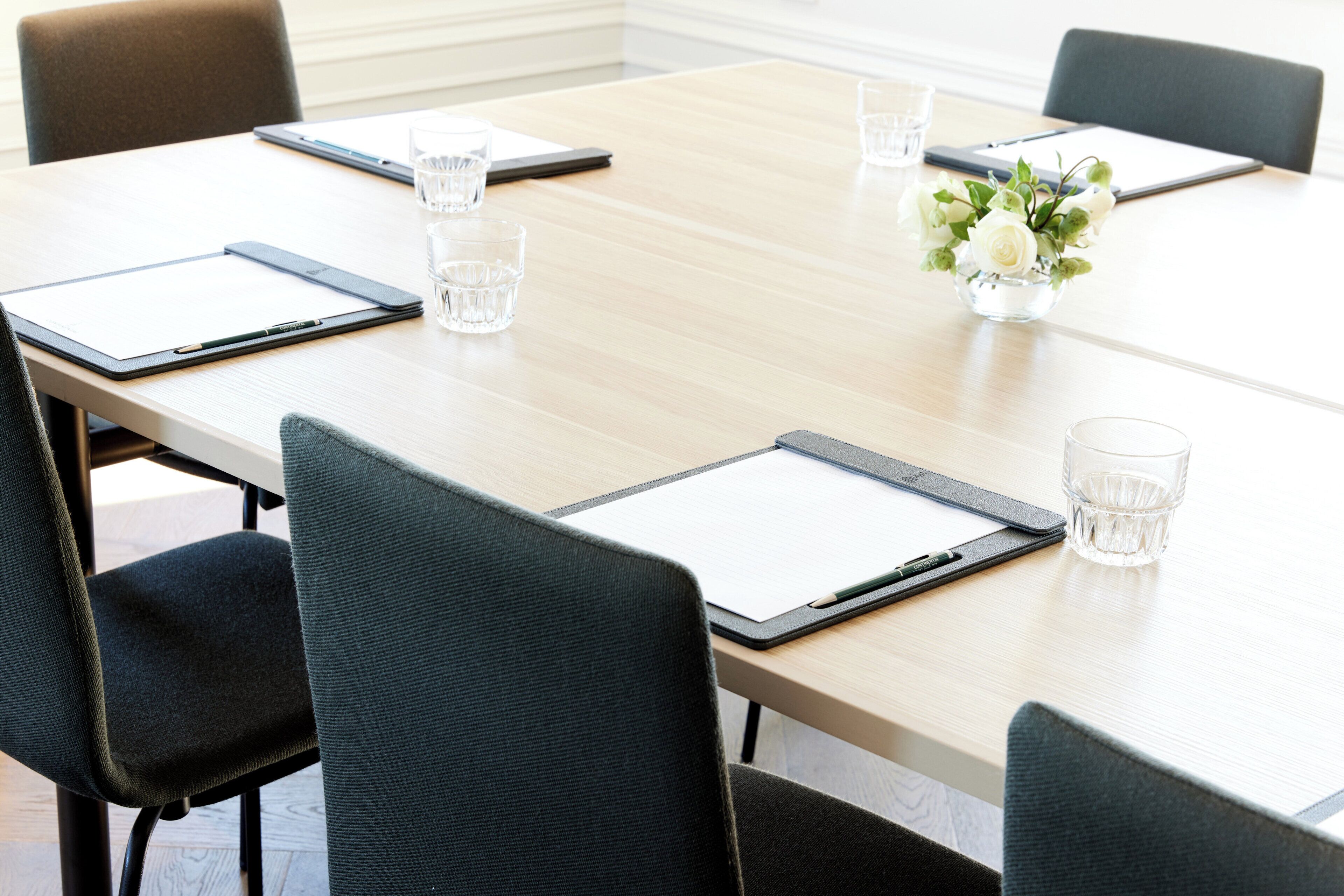 A conference table with clipboards, pens, and glasses.