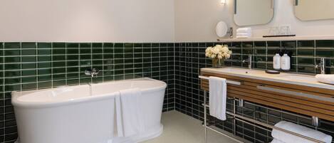 Un baño moderno con una bañera independiente, un tocador con espejo y un salpicadero de azulejos.