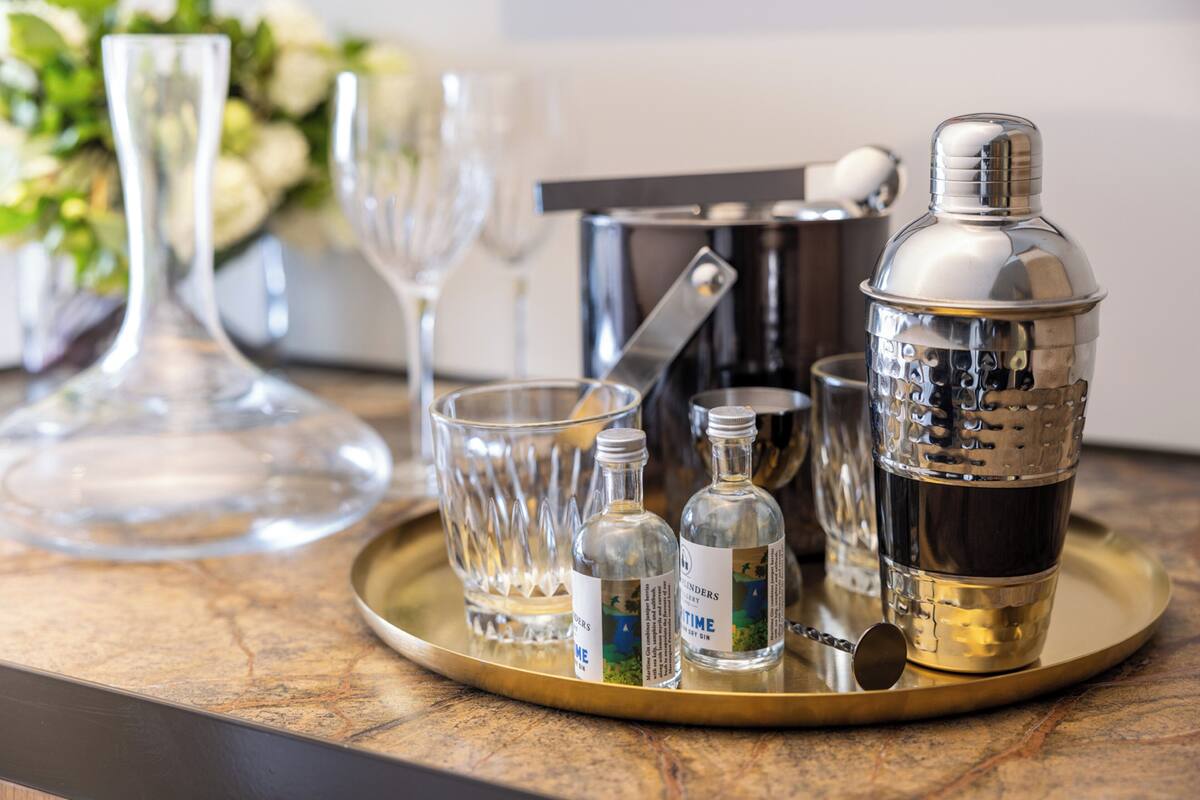 Een cocktailshakerset op een dienblad met glazen en flessen, waarschijnlijk voor een bar of evenement.
