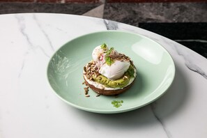 Een groen bord met een belegd broodje op een marmeren tafel.