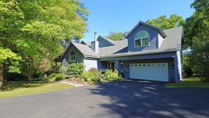 A two-story house with a garage, surrounded by trees and a well-maintained lawn.