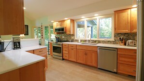 A modern kitchen with wooden cabinets, stainless steel appliances, and a large window providing natural light.