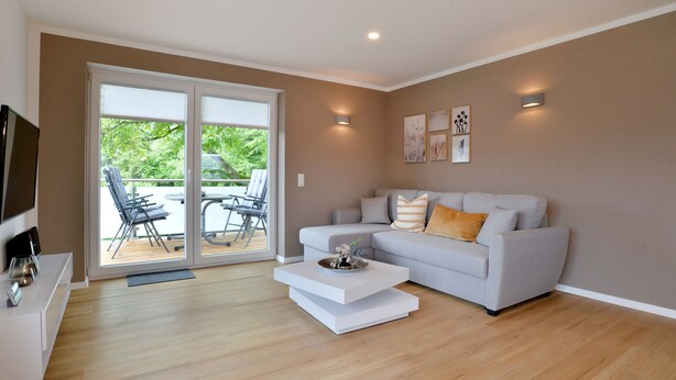 A modern living room with a grey sofa, a white coffee table, and a TV on a white cabinet. - Vacation apartment I Kleine - Eifel - Time out (Hambuch)