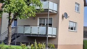 A multi-story residential building with a balcony, satellite dish, and a tree in the foreground. - Vacation apartment I Kleine - Eifel - Time out (Hambuch)
