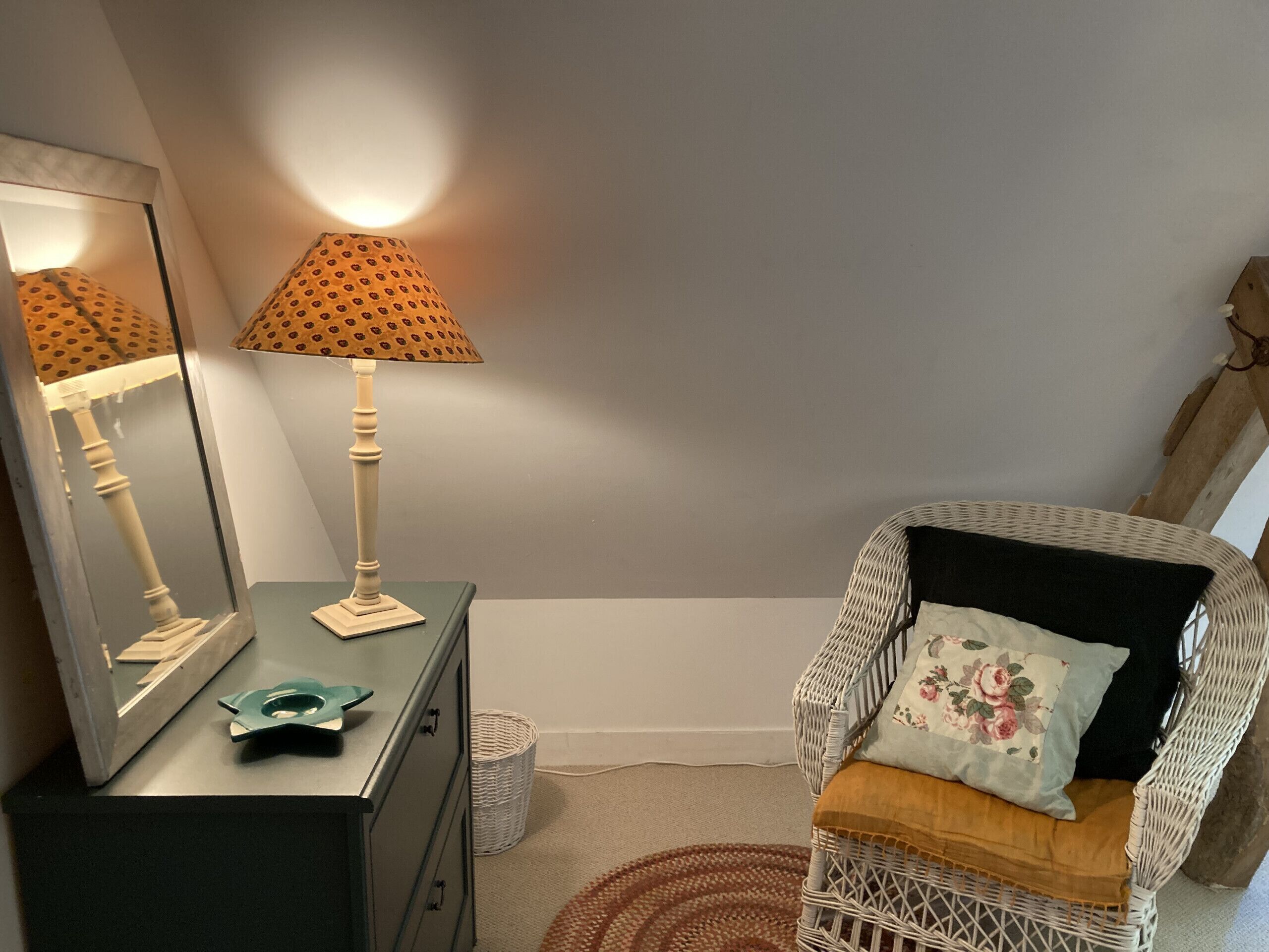 Una habitación con tocador, lámpara, silla y espejo.