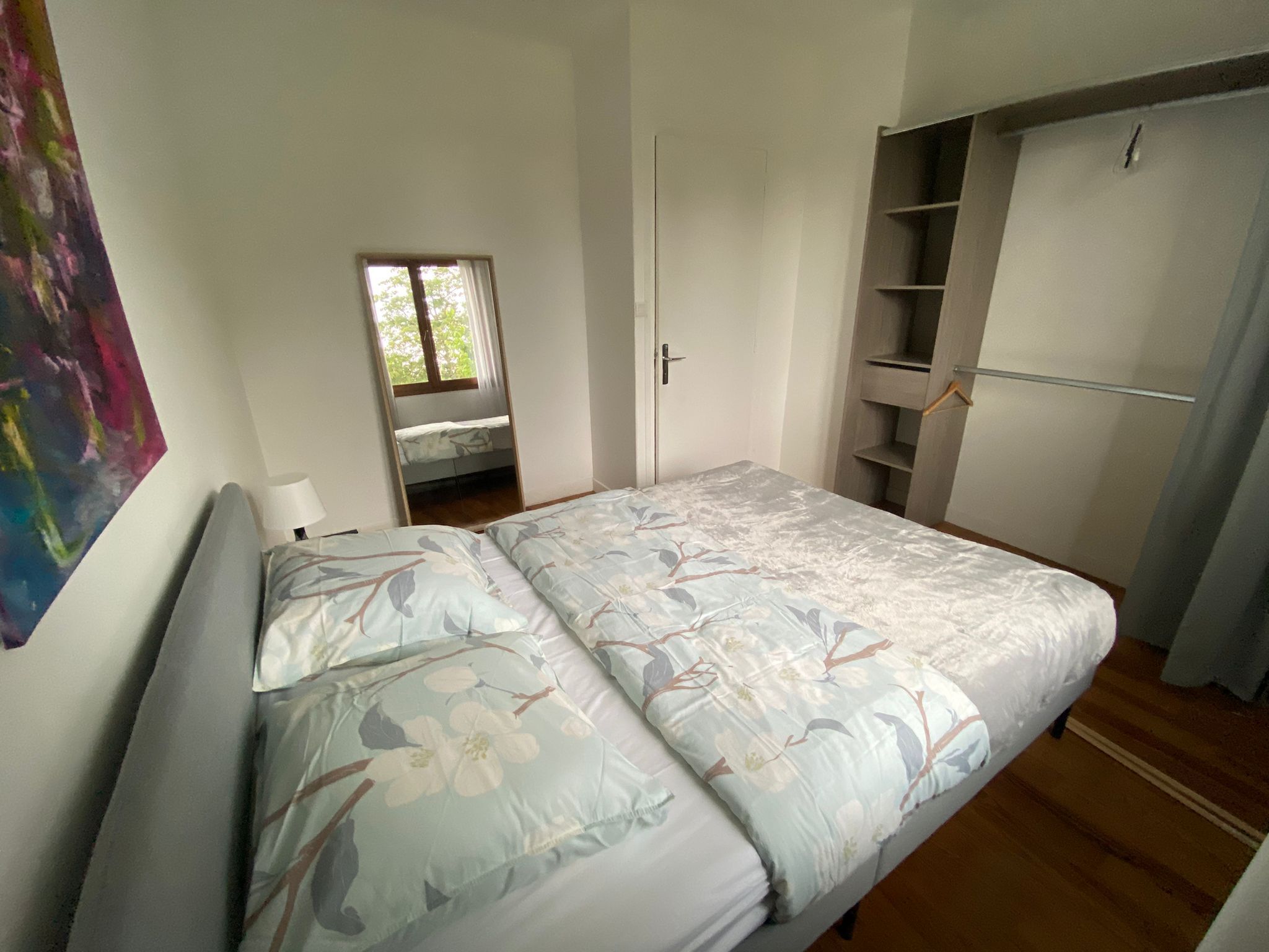 Una camera da letto con un letto, una finestra, un armadio e un quadro appeso al muro.