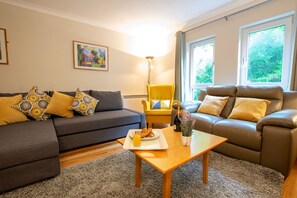 Relax in this stylish living room with a grey sofa, patterned cushions, a leather armchair, and a wooden coffee table.
