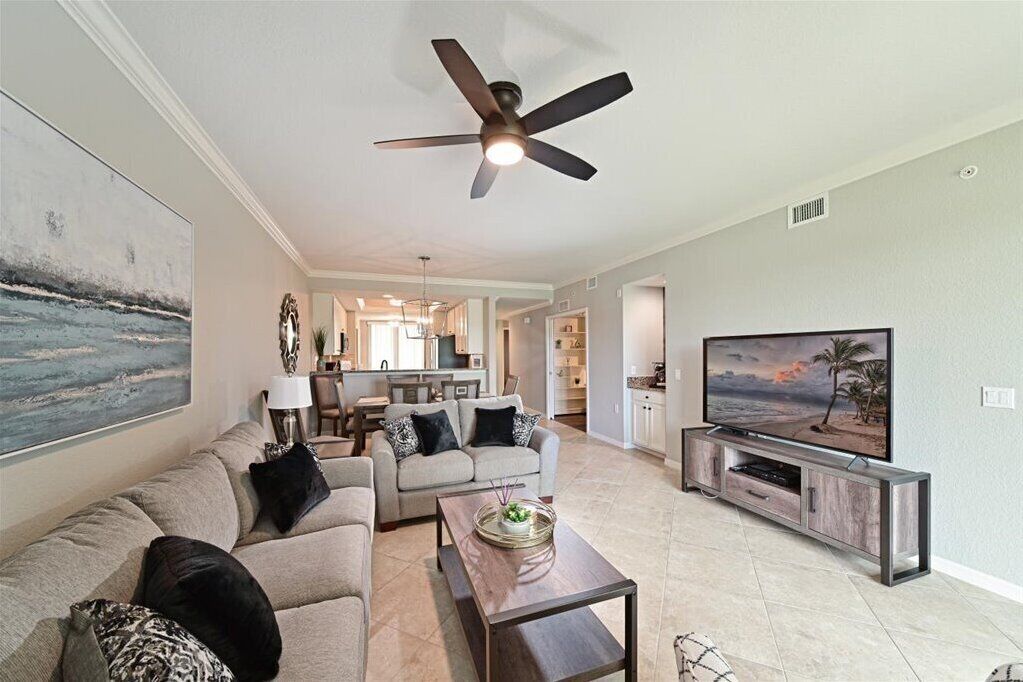 A modern living room with a sofa, coffee table, TV, and ceiling fan.