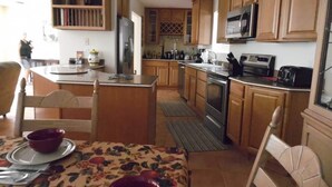 A kitchen with wooden cabinets, a central island, a microwave, and a stove. - Cisco Surprise with a SPA (Lake Havasu City)