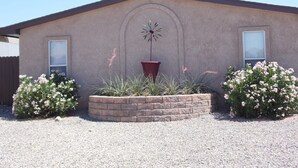 A building with a simple, single-story structure, a small garden area with various plants and flowers, and a wind chime hanging in the center. - Cisco Surprise with a SPA (Lake Havasu City)