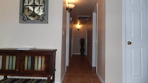 A hallway with a bench, a wall-mounted light fixture, and a door at the end. - Cisco Surprise with a SPA (Lake Havasu City)
