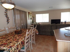 Un espacio habitable compacto con zona de comedor, sofá y televisor.